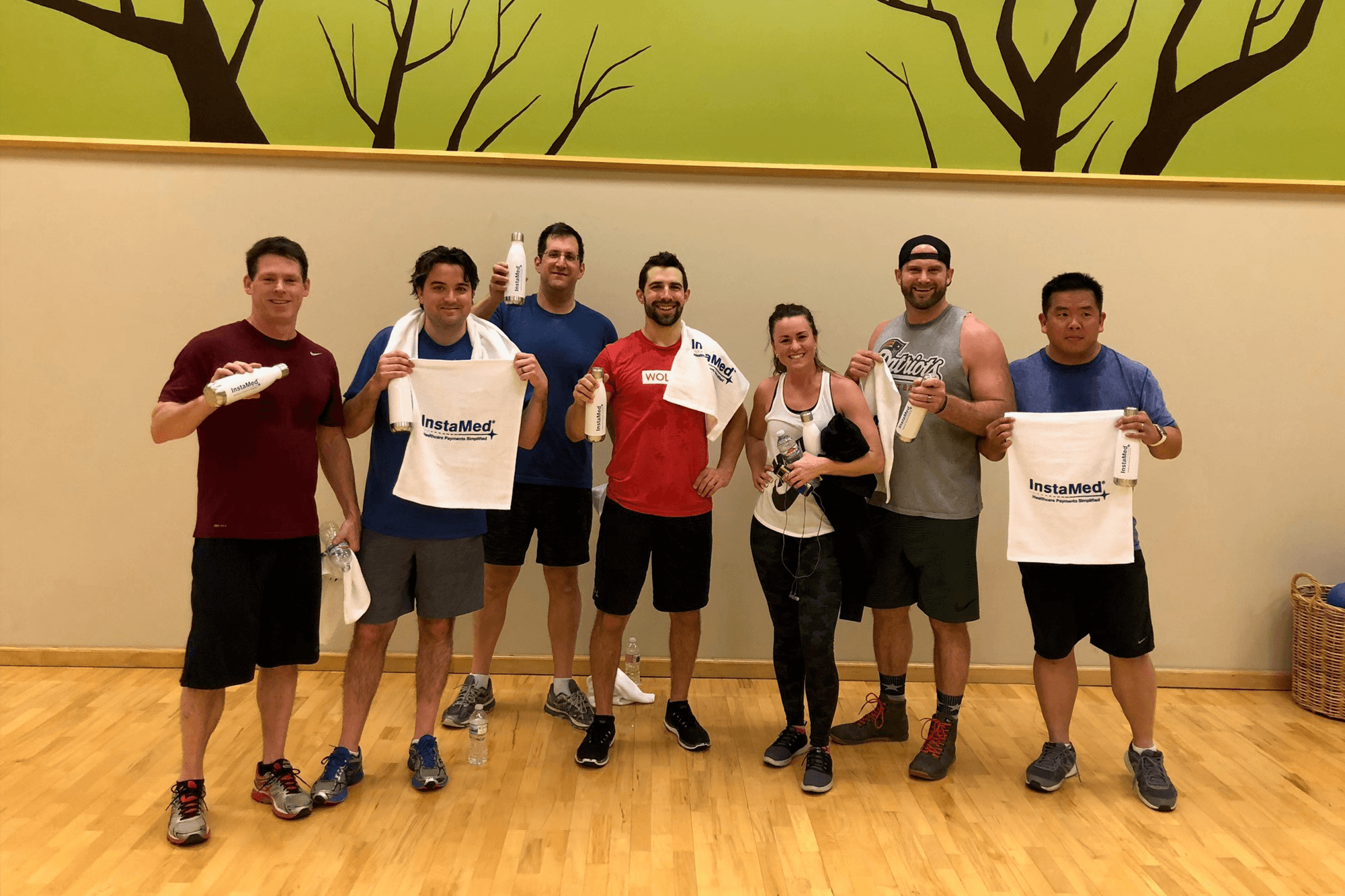InstaMed User Conference 2018 attendees stand and smile after completing a fitness bootcamp led by Ben Bartholomew.