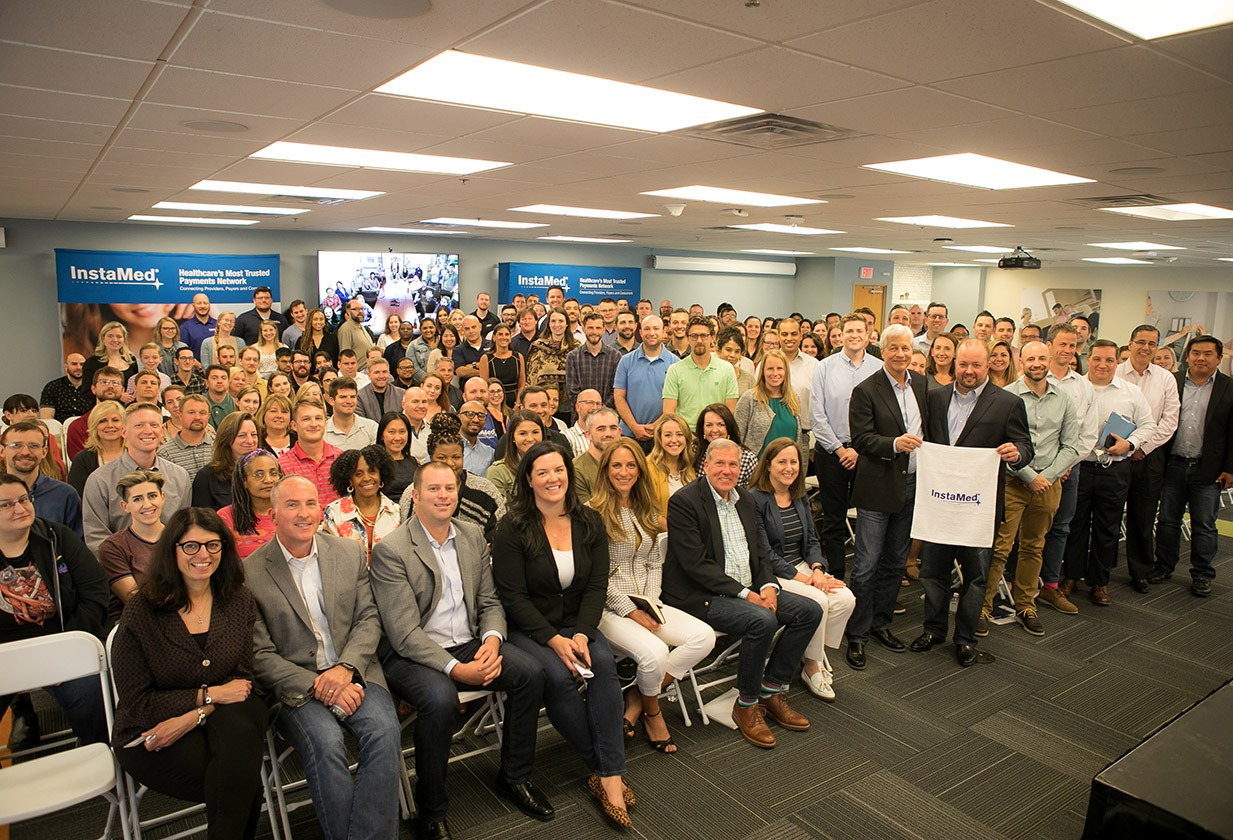 The packed conference room is all smiles as Jamie Dimon and Bill Marvin stand with InstaMed employees at the town hall.