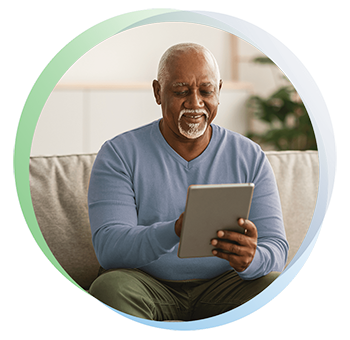 Older man smiles while holding an iPad to pay his healthcare bill.